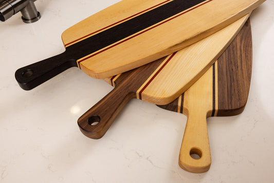 Collection de planches apéro artisanales en bois massif, détail des poignées et des différentes essences de bois.