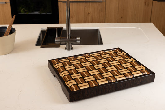 Planche à découper en bois précieux de bout, façonnée à la main en France, présentée sous un autre angle dans une cuisine moderne. Zebrano, noyer et érable, finition lustrée et rigole intégrée