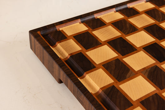 Détail sur la rigole à jus et la qualité de finition haut de gamme d'une planche à découper made in France en noyer, poirier et érable.