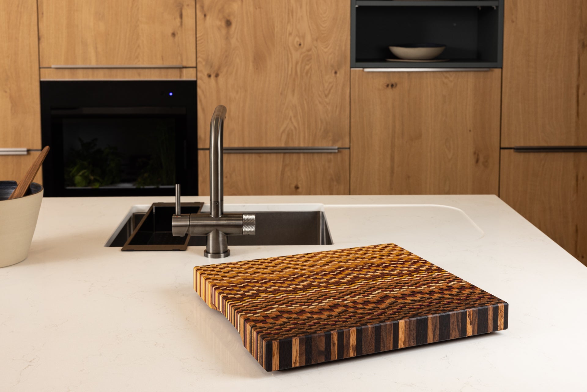 Planche à découper artisanale de luxe mise en situation sur un plan de travail moderne.