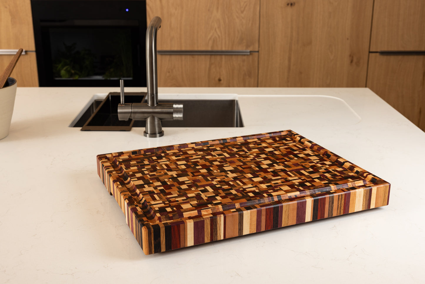 Planche à découper en bois de bout modèle Messiaen, pièce artisanale en bois précieux fabriquée en France, posée sur un plan de travail dans une cuisine moderne