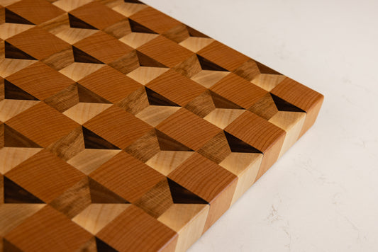 Vue de dessus incliné de la planche à découper Cube, révélant l’effet trompe-l’œil cubique saisissant, réalisée en bois de bout multi-essences, artisanat français haut de gamme.