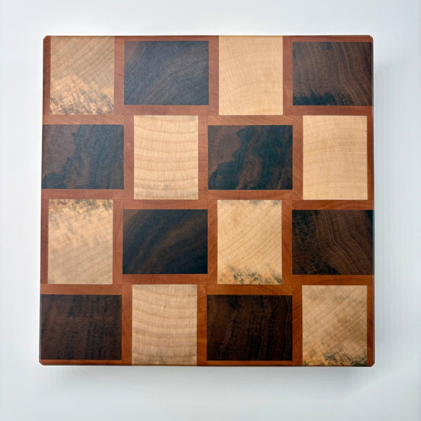 Vue de dessus d'une planche à découper artisanale à motif en damier. Fabrication made in France, 100% bois de bout, noyer, érable, poirier.