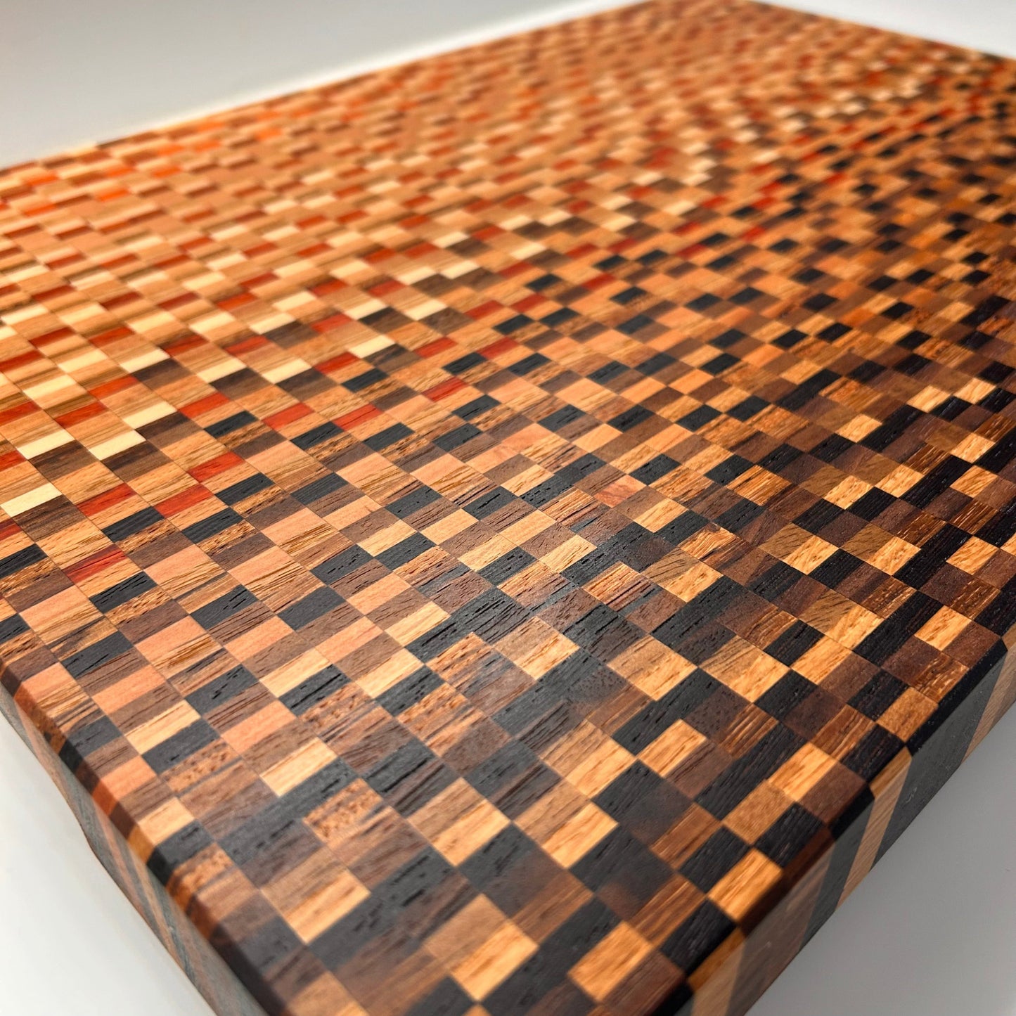 Vue rapprochée du motif graphique d’une planche à découper artisanale en bois massif multi-essences. Design moderne et haut de gamme.