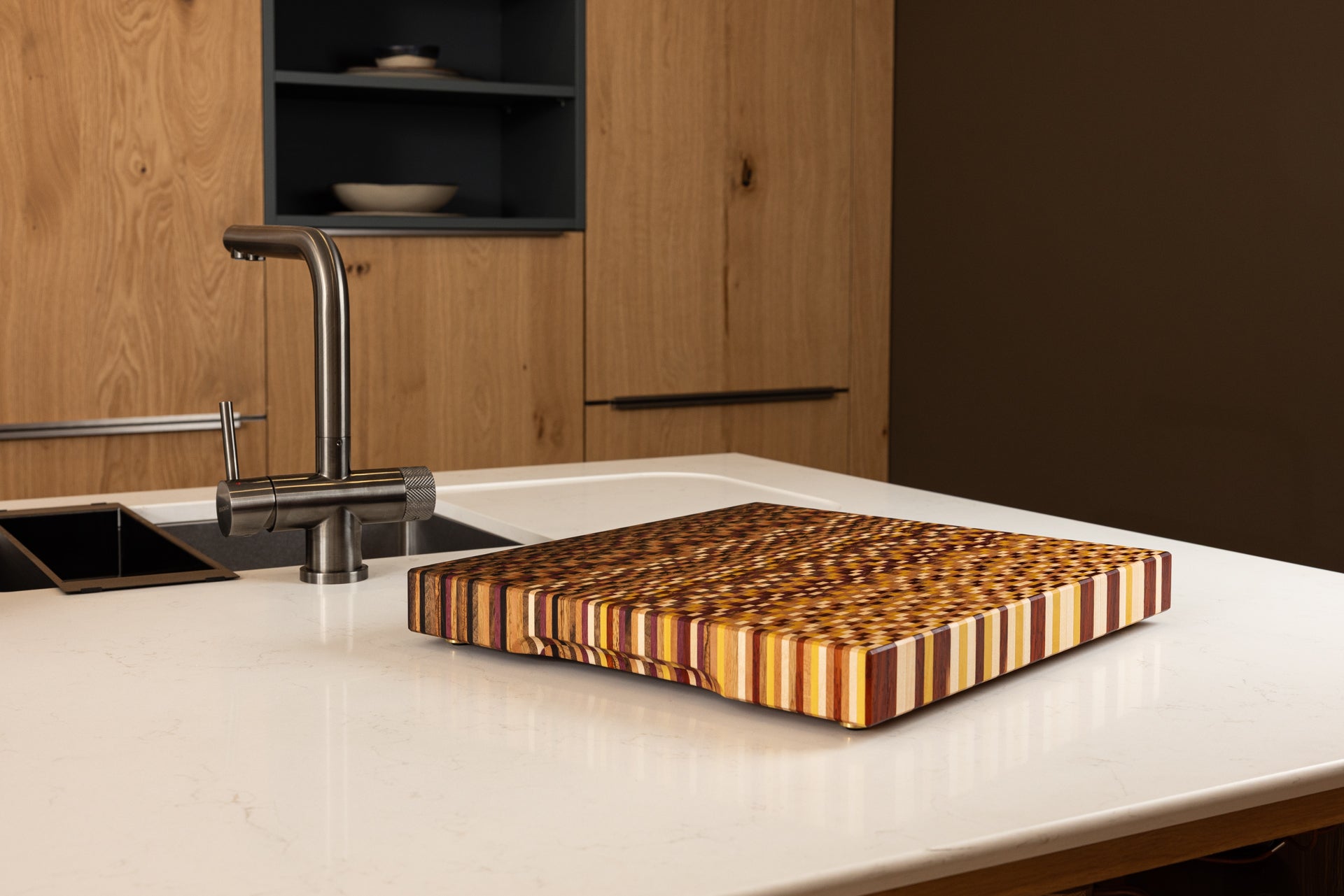 Planche artisanale 11 essences fabriquée en France et posé sur un plan de travail de cuisine.