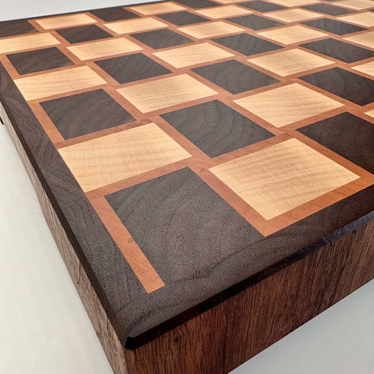 Planche artisanale haut de gamme, vue rapprochée du coin, motif en damier nyer, érable et poirier, sans rigole à jus