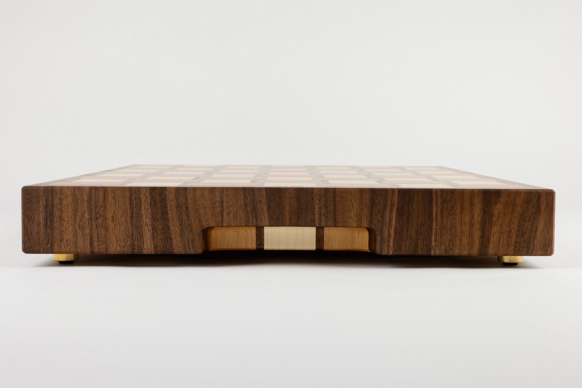 Planche à découper Berlioz en bois de bout multi-essences, vue latérale avec détail de la poignée fraisée élégante, motif damier tissé, artisanat français Made in France haut de gamme.