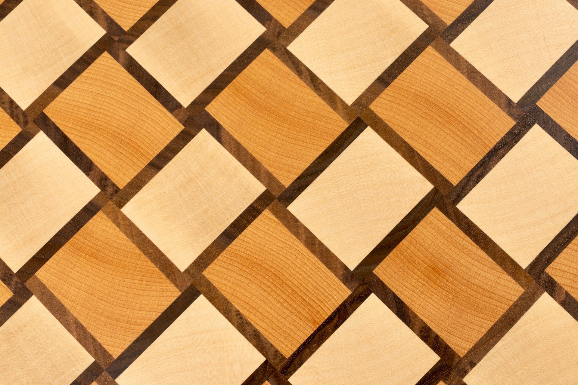 Vue rapprochée du motif damier tissé de la planche à découper Berlioz, en bois de bout hêtre, érable et noyer américain, modèle de luxe Made in France avec finitions haut de gamme.
