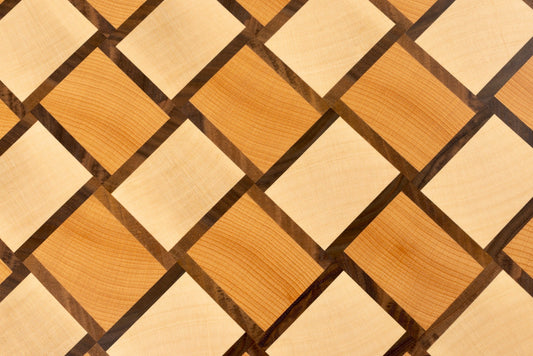 Vue rapprochée du motif damier tissé de la planche à découper Berlioz, en bois de bout hêtre, érable et noyer américain, modèle de luxe Made in France avec finitions haut de gamme.