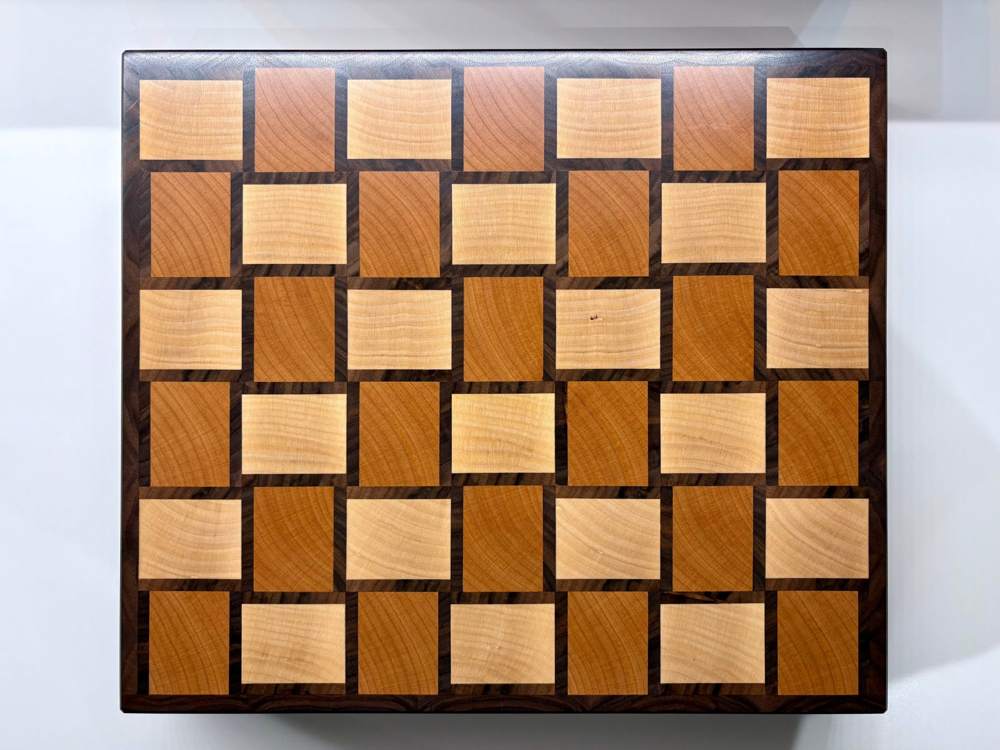 Planche à découper Berlioz Mezzo en bois de bout, fabriquée en France en hêtre, noyer américain et érable, avec poignées intégrées et pieds en laiton.