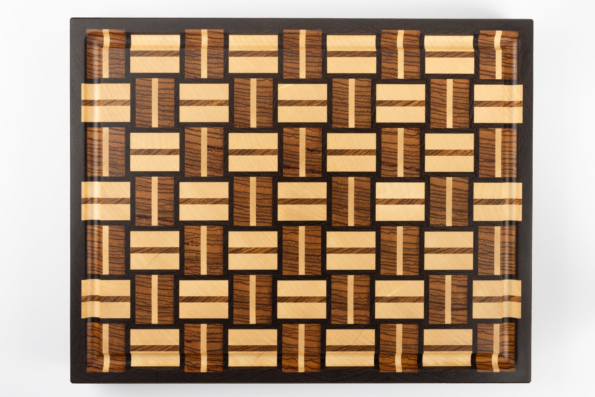 Planche à découper premium Berlioz en bois de bout, vue de dessus avec son design graphique damier tissé, essences précieuses wengé, zebrano et érable, finitions artisanales de prestige Made in France.