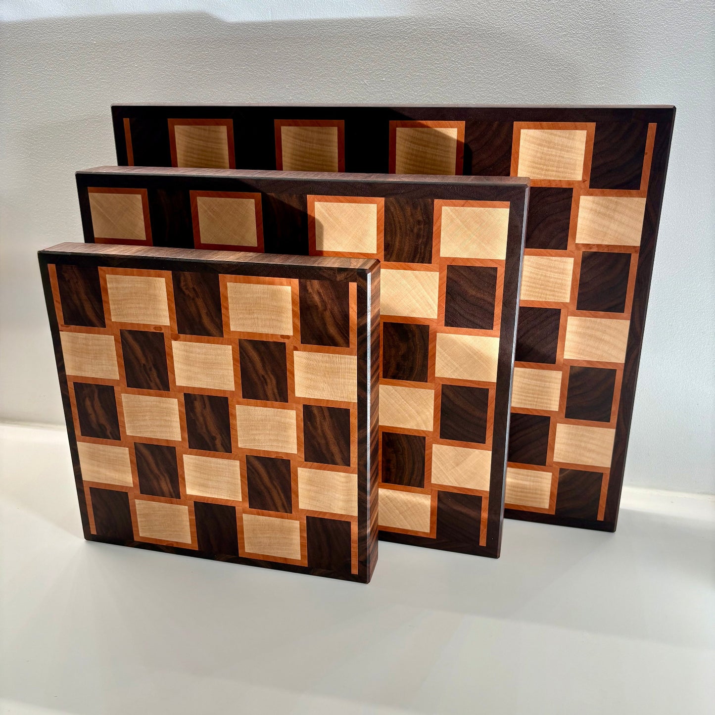 Aperçu des planches à découper haut de gamme en bois de bout, motif à damier et disponibles en 3 tailles. Fabrication artisanale en France.