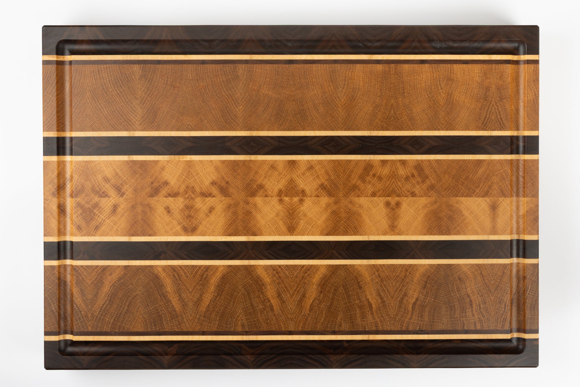 Vue de dessus de la planche à découper en bois de bout artisanale Ravel, design intemporel à bandes en chêne français, noyer américain et érable, avec veinage disposé en diamant pour un rendu graphique raffiné, fabrication artisanale haut de gamme.