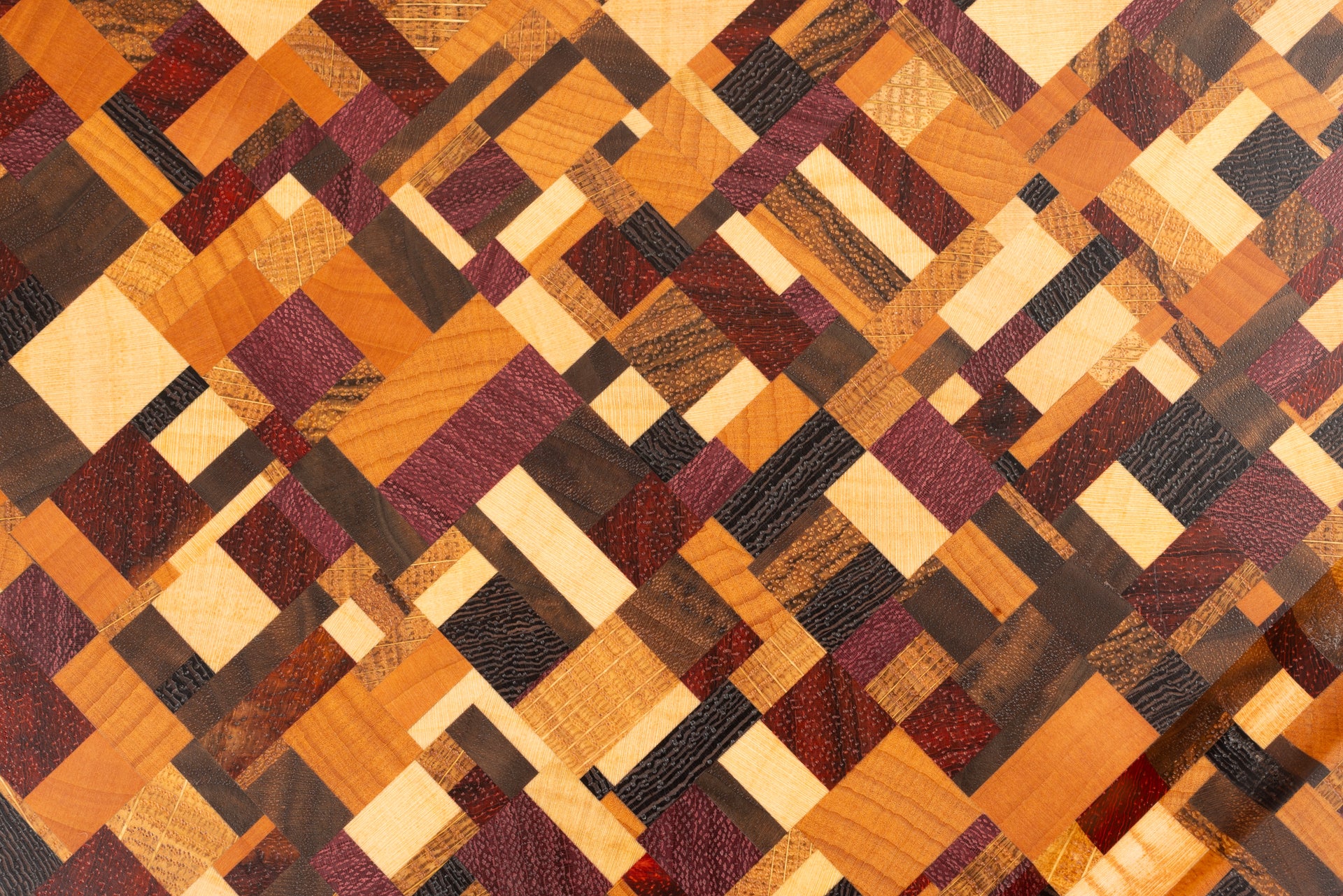 Gros plan sur le motif coloré et original de la planche à découper artisanale Messiaen en bois de bout, composée de 9 essences nobles : érable, hêtre, chêne français, noyer américain, wengé, padouk et amarante.