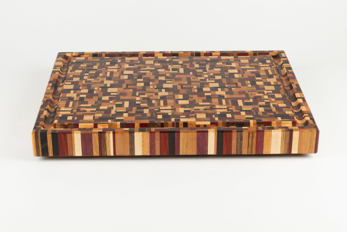 Vue de face de la planche à découper artisanale Messiaen, révélant son design graphique unique en bois de bout multi-essences nobles.