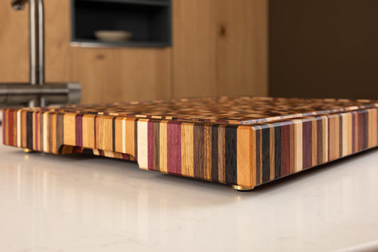 Planche à découper de luxe Messiaen, vue de trois quarts révélant son design graphique et colorés en bois de bout multi-essences, dans une cuisine haut de gamme en chêne.