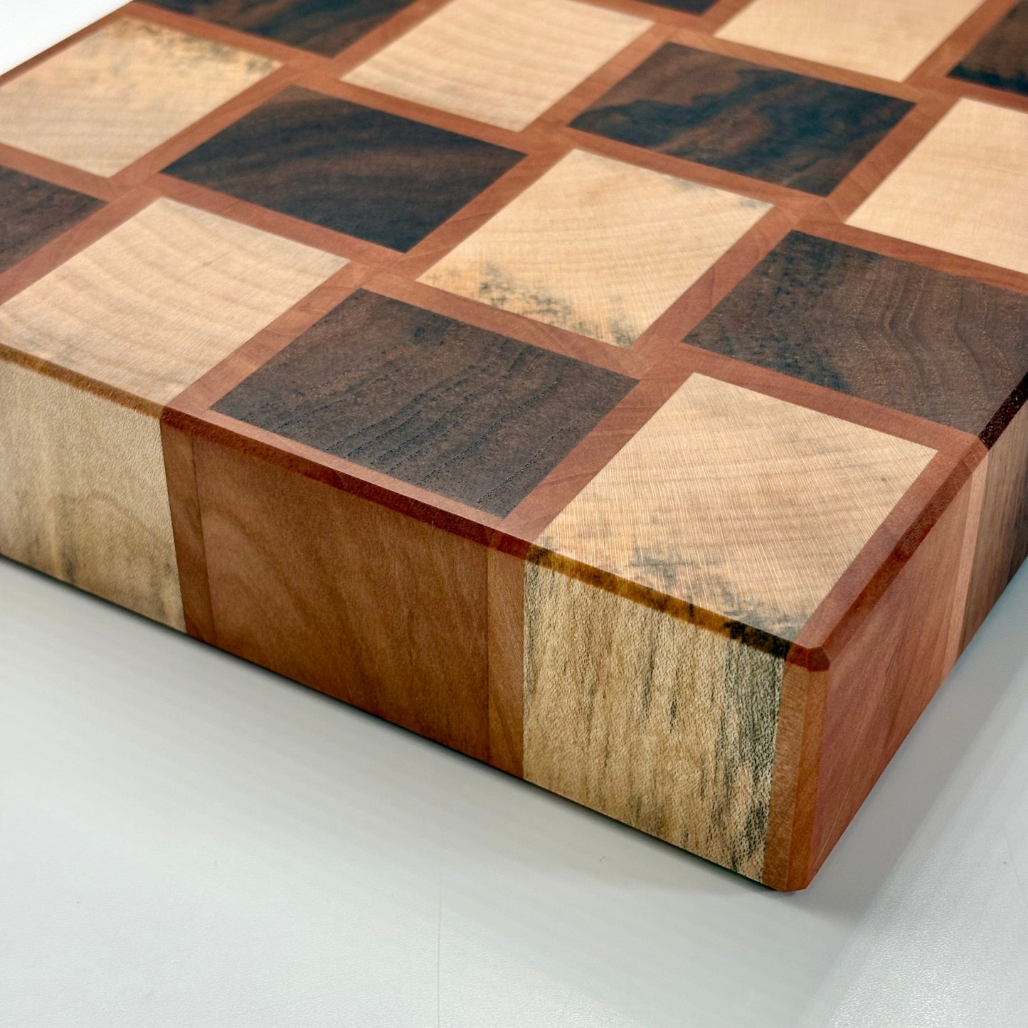 Vue de la tranche d'une planche à découper artisanale en poirier, noyer et érable echauffé