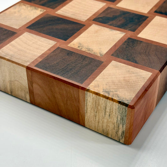 Vue de la tranche d'une planche à découper artisanale en poirier, noyer et érable echauffé