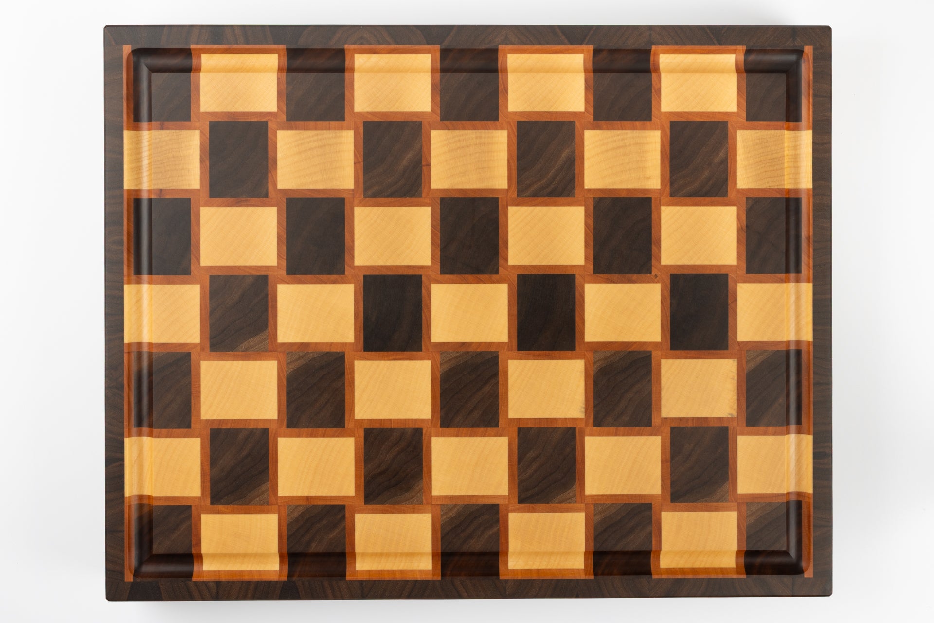 Vue de dessus complète d’une planche à découper artisanale en bois de bout, motif damier tressé en poirier, érable et noyer américain.