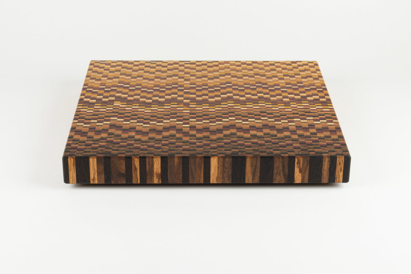 Vue plongeante sur le dégradé sombre d'une planche à découper graphique en bois de bout artisanale.