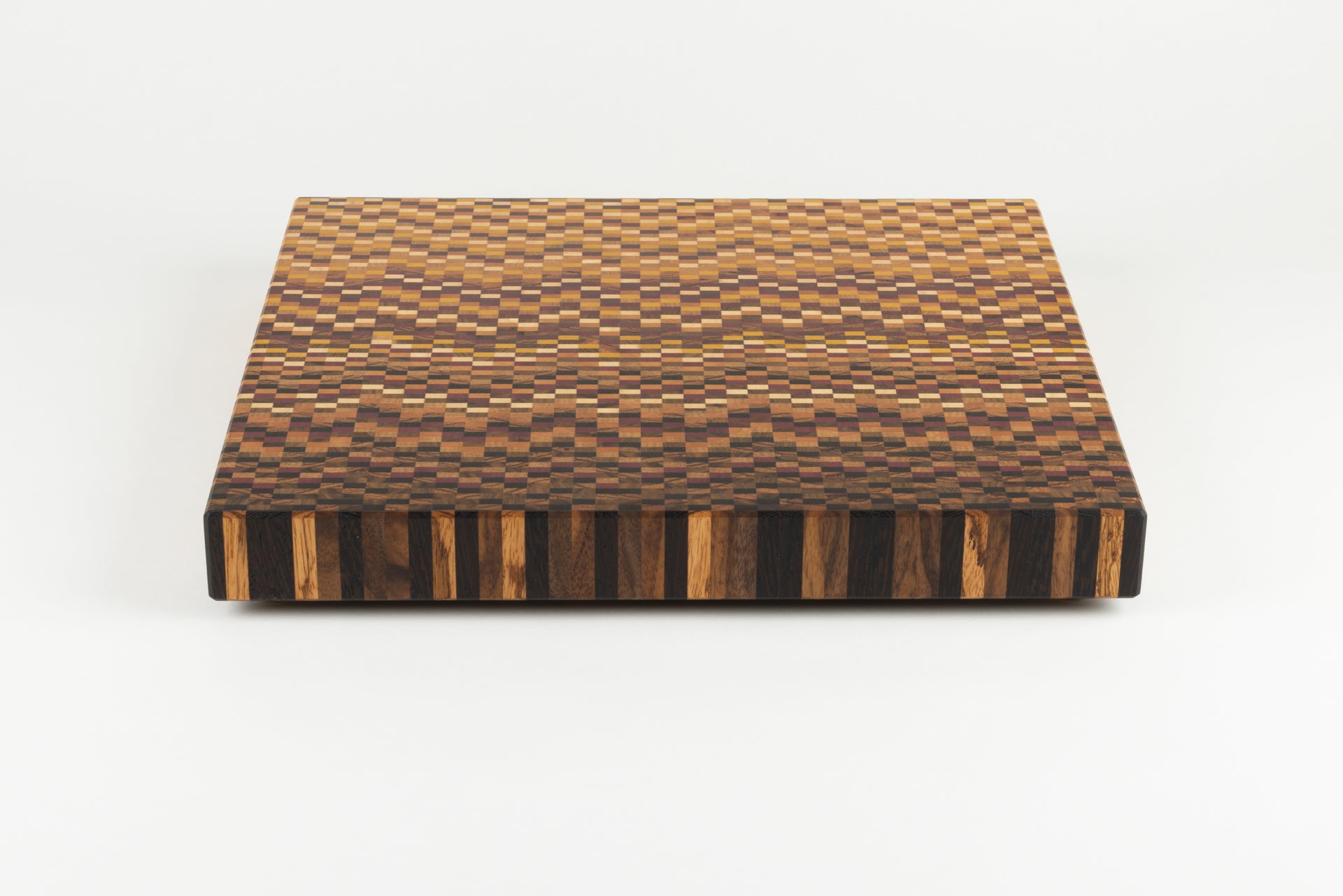 Vue plongeante sur le dégradé sombre d'une planche à découper graphique en bois de bout artisanale.