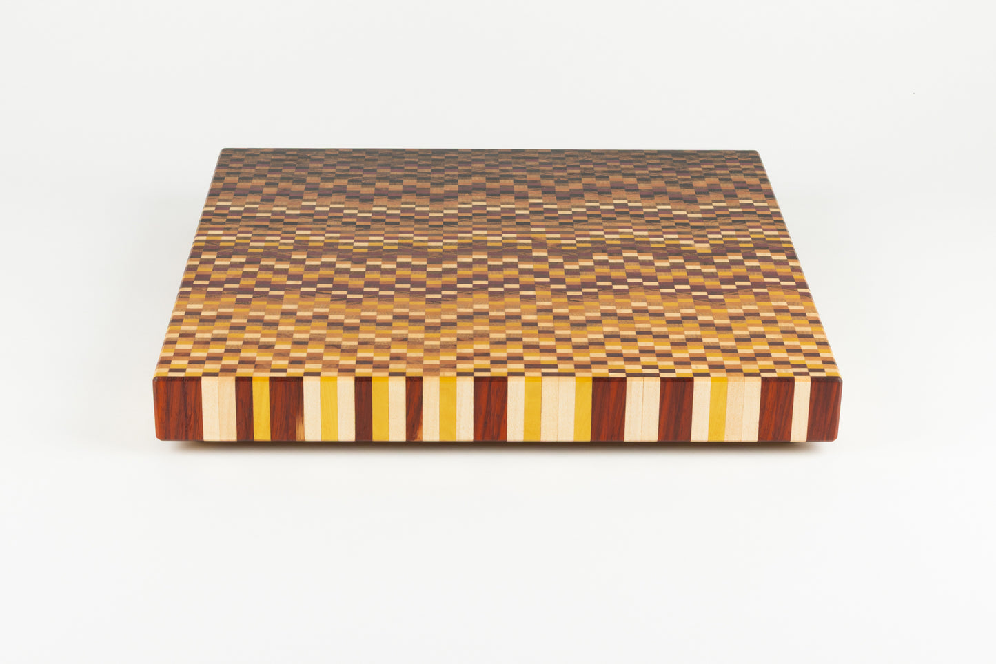 Vue plongeante sur le motif en dégradé de bois de bout 11 essences d'une planche à découper artisanale haut de gamme.