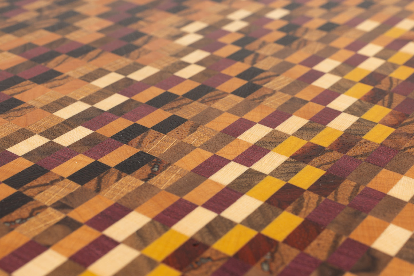 Gros plan sur le motif d'une planche à découper artisanale en bois de bout réalisé avec 11 essences de bois précieux