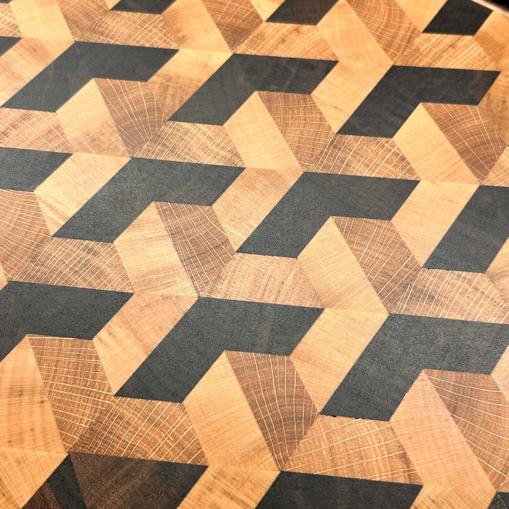 Détail du motif trompe-l’œil effet 3D en noyer américain, chêne de Bourgogne et érable sur une planche à découper en bois de bout