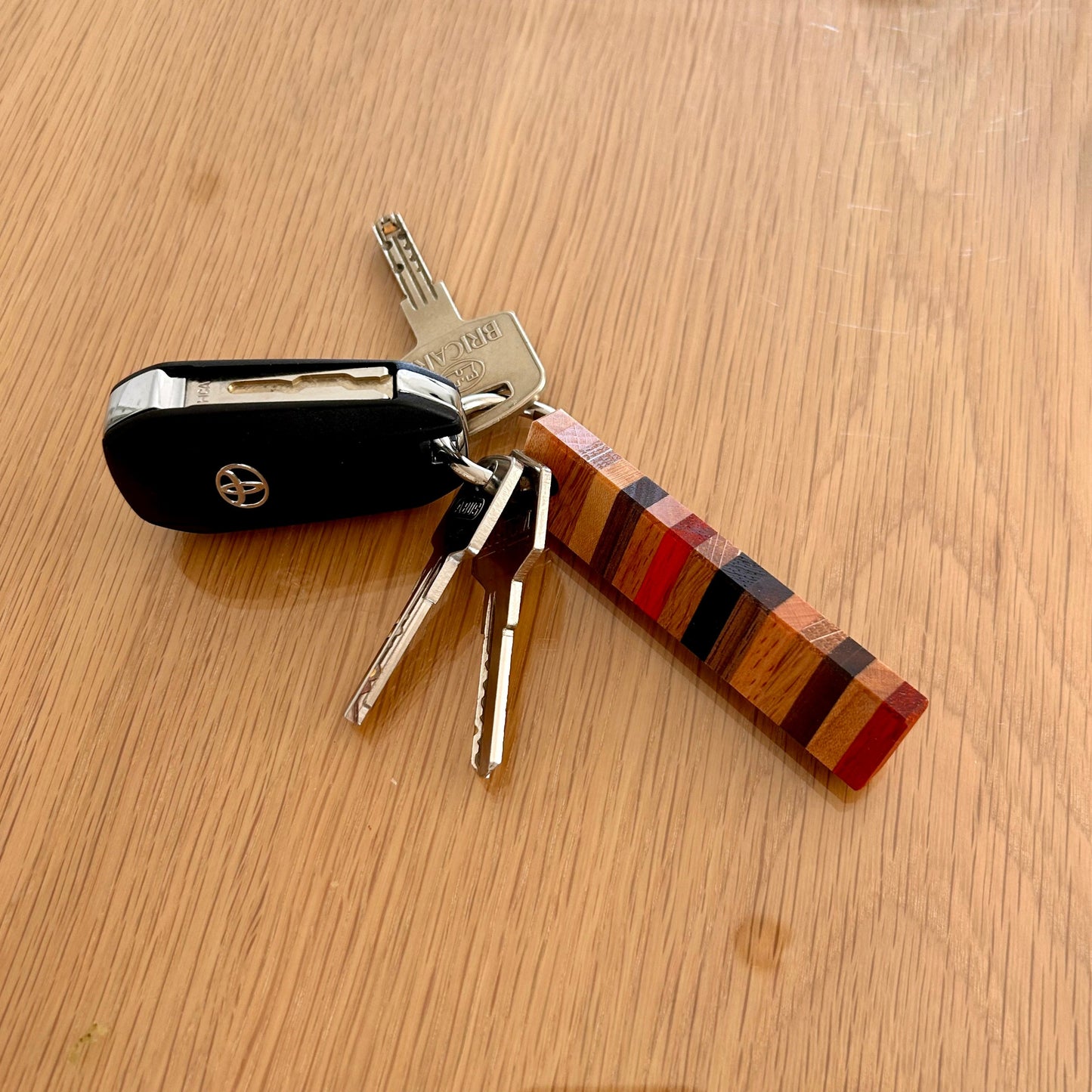 Mise en situation d'un trousseau de clés avec le porte-clés en bois 8 essences à design rayé "Signature"